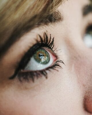 Close-up of a woman's eye with long, dark eyelashes showing bimatoprost eyelash growth results