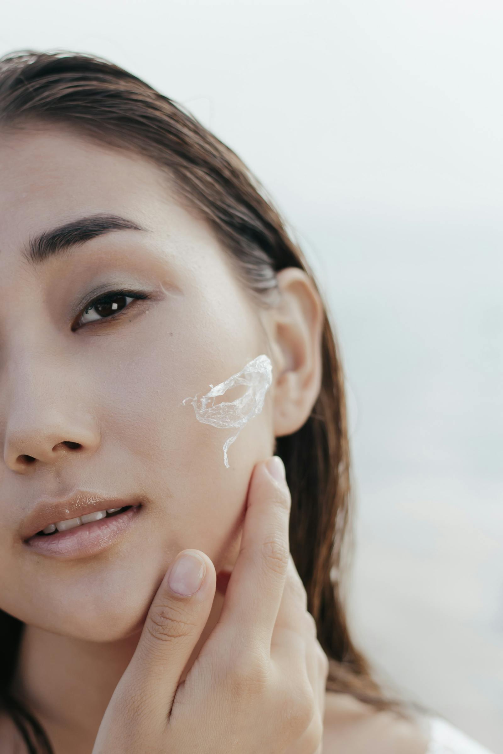 Close-up of woman applying retinoid cream to cheek showing clear glowing skin from consistent use