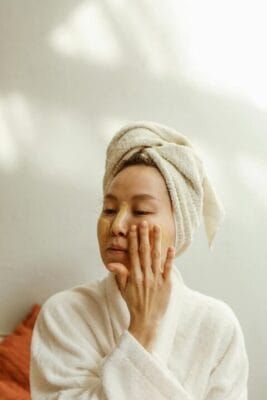 Woman applying facial cream in relaxed setting — cosmetic peptide research
