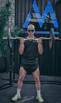 Athletic man lifting barbell indoors — muscle recovery research