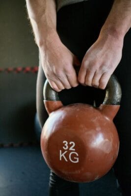 Hands holding kettlebell during gym workout — tissue-repair research
