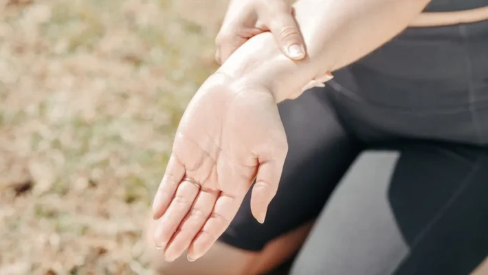 Person stretching and holding their wrist due to joint pain
