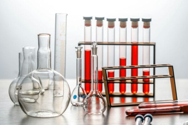 Laboratory glassware with red liquids on test tube rack — peptide cycling research