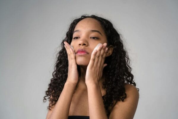 Young woman applying skincare cream to face — copper peptide research