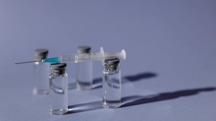 Syringe balanced on vials illustrating injectable HCG vs sublingual drops