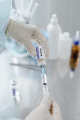 Sterile gloved hands drawing medication from a vial — HCG reconstitution and BAC water protocol