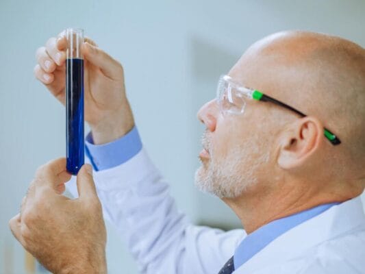 Scientist examining blue liquid in test tube — IGF-1 research