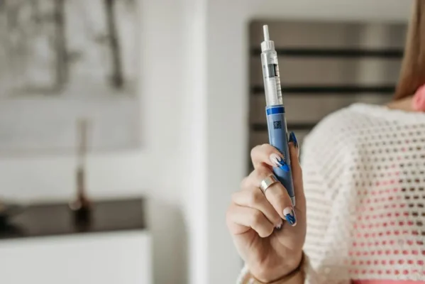 Woman holding an insulin-style injection pen — dosage chart context