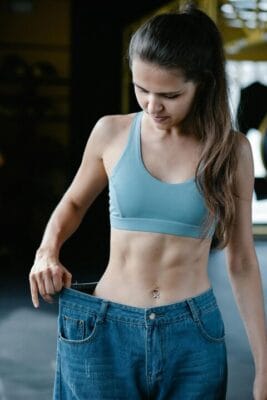Person showing weight loss success in oversized jeans — GLP-1 weight loss research