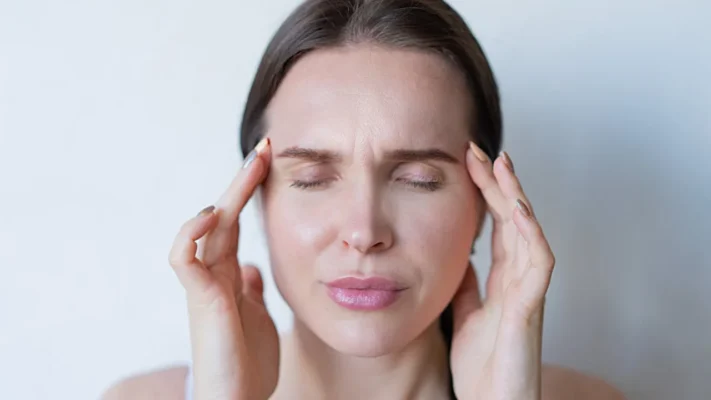 Woman holding temples during migraine attack — illustrating acute migraine pain treated by rizatriptan (Rizact)
