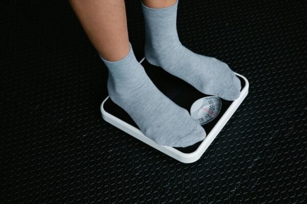 Feet in grey socks on a bathroom scale — illustrating weight monitoring after stopping Ozempic and the rebound effect