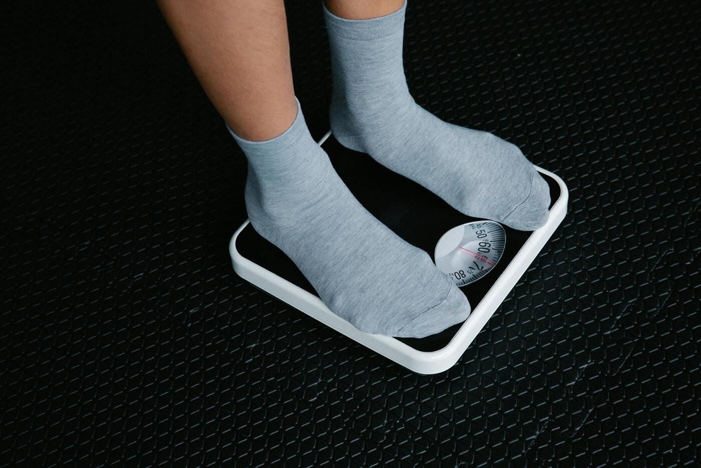 Feet in grey socks on a bathroom scale — what happens when you stop taking Ozempic and the rebound effect on body weight
