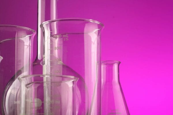 Clear glass laboratory flasks on purple backdrop — peptide storage research