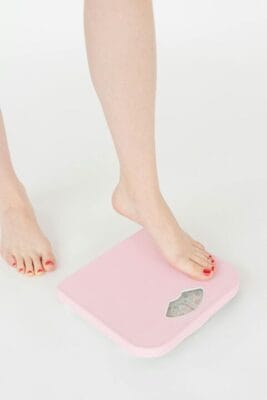 Person stepping onto weight scale — obesity research