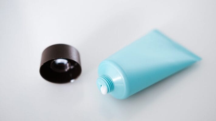 Open topical anesthetic cream tube on clinical background for lidocaine prilocaine product comparison