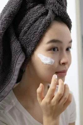 Woman applying moisturizer as part of skincare routine — tretinoin sandwich method