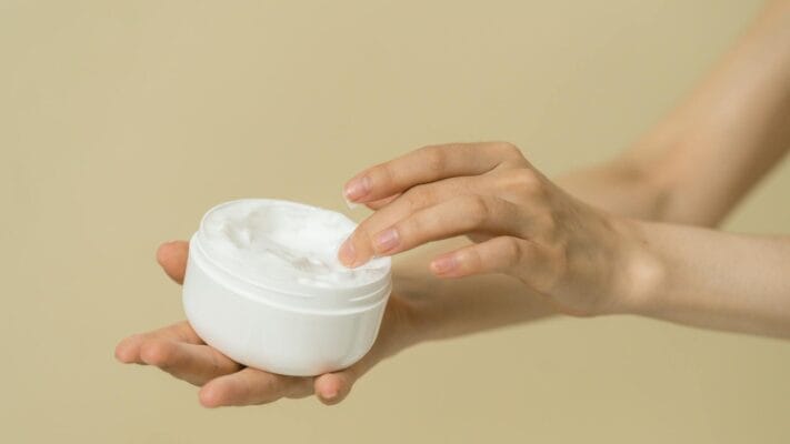 Hands holding open cream jar — tretinoin vs adapalene retinoid comparison guide