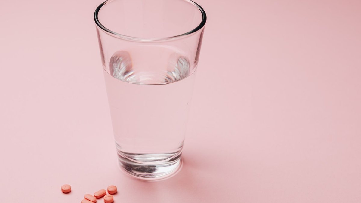 Glass of water with medication pills, representing the best time to take levothyroxine thyroid medication